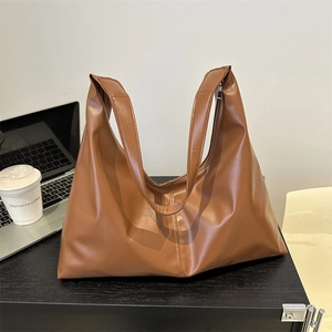 Brown soft faux leather shoulder bag with wide straps for office commute on desk