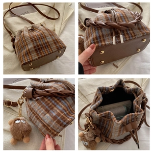 Detailed view of checkered bucket bag featuring reinforced base with metal studs and plush charm