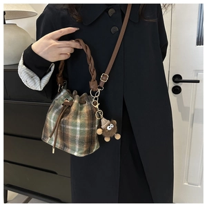 Close-up of vintage plaid bucket bag with soft wool texture and a cute bear charm