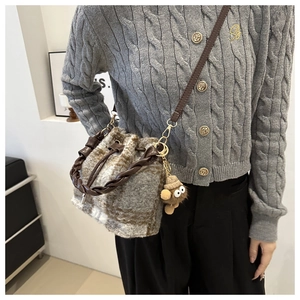 Detail of checkered faux fur bucket bag with woven leather handle and plush eye charm