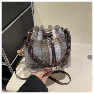Detail of wool bucket bag with plaid pattern, braided leather handle and drawstring