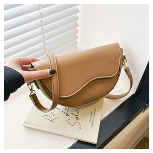Close-up of camel brown matte leather saddle bag with gold hardware and embossed logo