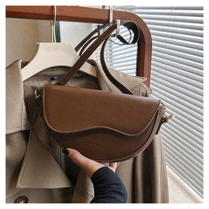 Detailed view of brown faux leather saddle bag with stitching and adjustable shoulder strap