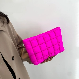 Pochette matelassée rose fluo tendance avec motif à carreaux tenue par un mannequin