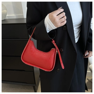Detail of red croc-embossed underarm bag shown as a shoulder bag on a model