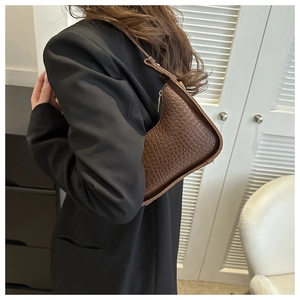 Detailed view of the brown crocodile pattern texture and zipper on the half-moon shoulder bag