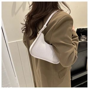 Close-up of white crocodile embossed texture on leather hobo bag with gold zipper detail