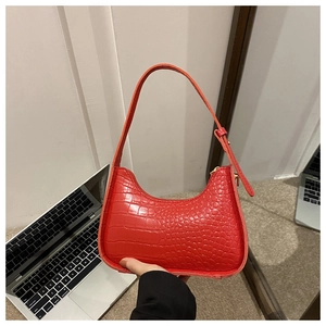 Detail of red crocodile texture on hobo bag with metallic shoulder strap buckle