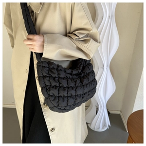 Detail of black quilted puffer bag with textured bubble fabric worn by a model