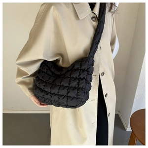 Detail of black quilted cloud crossbody bag featuring puffy nylon texture and wide strap