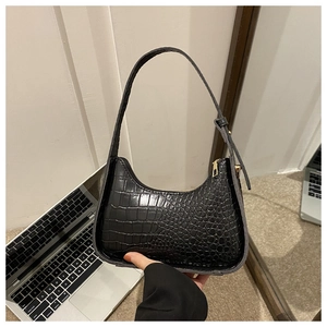 Close-up of black crocodile pattern faux leather texture with gold zipper on hobo bag