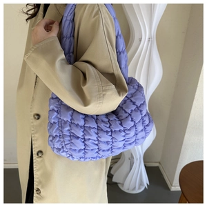 Macro detail of lavender quilted nylon cloud bag texture and stitching on crossbody strap