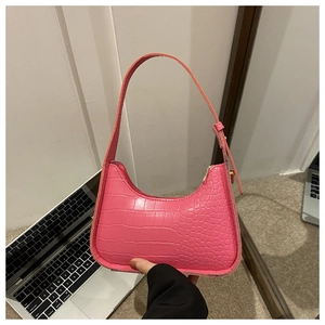 Detail of bright pink crocodile embossed underarm bag with zipper closure in PU leather