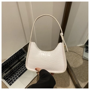 Detail of white crocodile texture underarm bag with elegant gold hardware accents