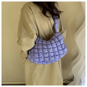 Detail of lavender quilted bubble shoulder bag paired with beige trench coat