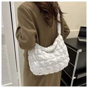 Close-up of a white quilted shoulder bag with soft padded diamond stitching on a model