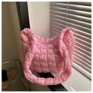Close-up of pink quilted puffer shoulder bag with textured fabric in soft window light