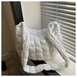 Detail of white quilted cloud bag featuring shiny nylon texture and soft padded shoulder strap