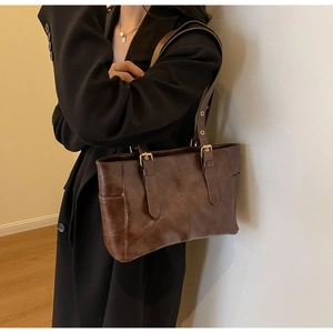 Detalle de bolso de hombro vintage marrón con correas ajustables y herrajes dorados