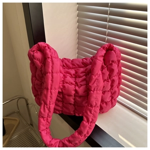Detail shot of hot pink quilted puffer shoulder bag with soft textured fabric finish