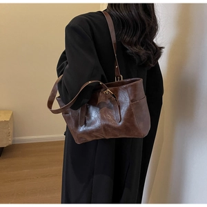 Vista lateral de bolso tote vintage marrón oscuro con hebillas metálicas doradas