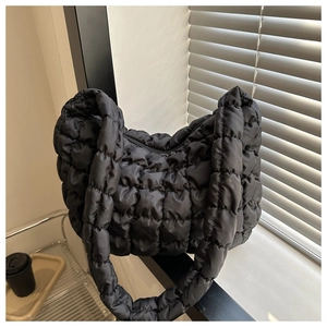 Detail shot of the black quilted bubble texture and zipper closure on a cloud-style bag