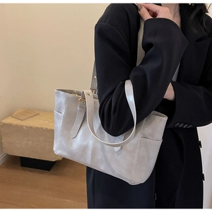 Detalle del bolso tote de cuero encerado gris claro con bolsillo lateral en la modelo