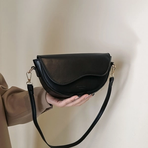 Minimalist black PU leather saddle bag with gold hardware shown as hand-held shoulder bag