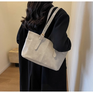 Detalle de correa ajustable con hebillas doradas en un bolso tote beige de gran capacidad
