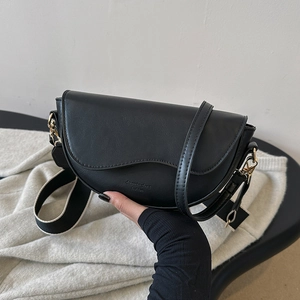 Minimalist black saddle bag with wavy flap design and two interchangeable shoulder straps