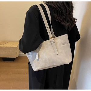 Detalle del bolso tote de cuero gris claro con hebilla metálica elegante en la correa de hombro