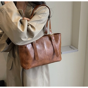 Vista detallada del bolso tote vintage marrón con correas decorativas y hebillas de oro