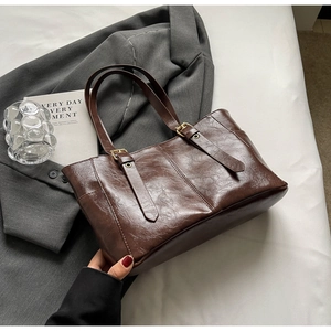Detalle del bolso tote vintage de cuero encerado marrón con hebillas doradas