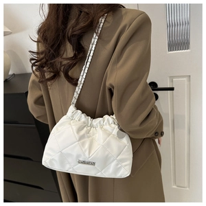 Détail du sac seau matelassé blanc avec logo métallique et bandoulière chaîne sur modèle