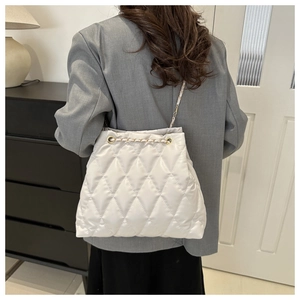 Detailed close-up of white quilted bucket bag featuring a woven chain strap and drawstring