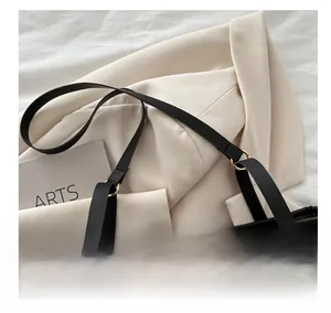 Detail of brown quilted tote bag with black leather strap and gold ring connector