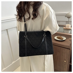 Detail of a black quilted tote bag with leather straps on a stylish French lifestyle background