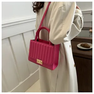 Rose pink quilted handbag with gold clasp worn by a model in a casual street setting