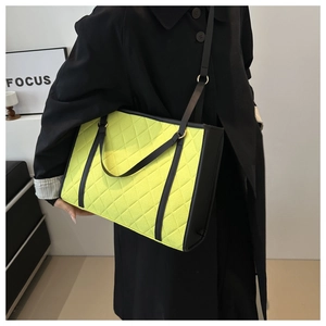 Macro detail of fluorescent yellow quilted tote bag with black handles and metal hardware