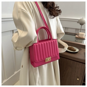 Detail of rose pink quilted crossbody bag with gold metallic lock and pleated texture