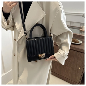 Detail of a vintage black flap bag with wave quilting and a gold metal twist lock