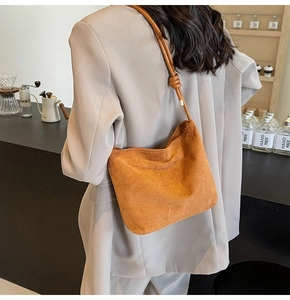 Detail of a brown suede tote bag with a unique knotted strap and gold metal hardware
