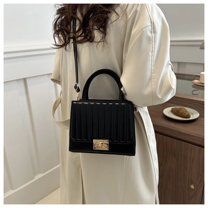Detail of black leather crossbody bag with pleated texture and gold square rotary lock