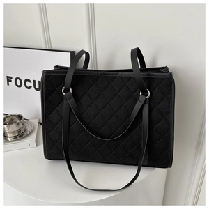 Detail of black quilted fleece tote bag featuring gold metal rings and leather straps