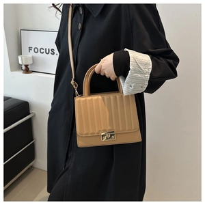 Detail of khaki square handbag with metal buckle and textured vertical stripes pattern