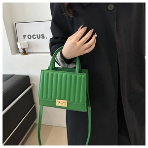 Detailed view of the emerald green quilted handbag with a gold square lock and handle