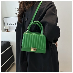 Detail of bright green crossbody bag with vertical embossed stripes and gold lock buckle