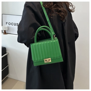 Detail of bright green pleated handbag featuring gold metal clasp and adjustable strap