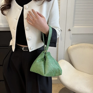 Detalle de un bolso triangular de pedrería verde combinado con un atuendo casual moderno