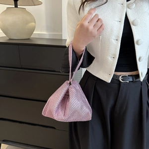 Vista detallada de bolso de mano triangular con pedrería rosa y atuendo sencillo
